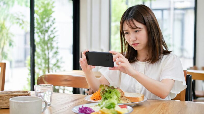 Xperia 10 VIのカメラ性能に不安を感じながら料理を撮影する日本人女性のイメージ画像