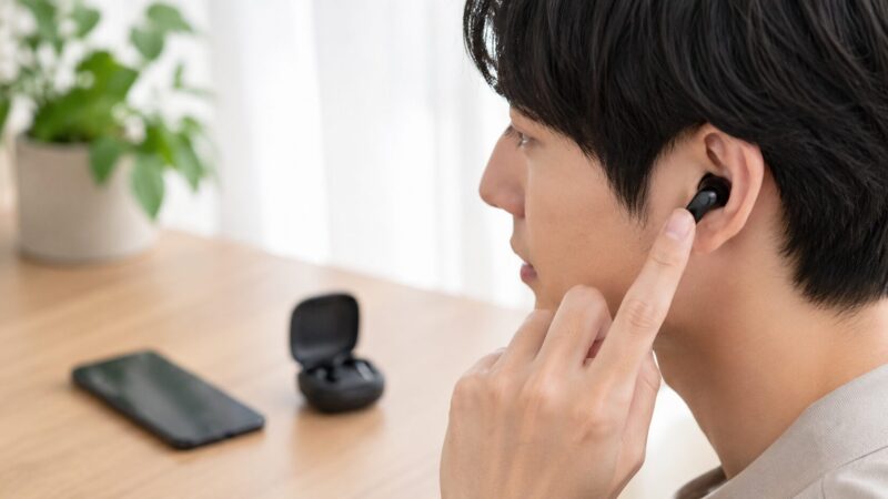 完全ワイヤレスイヤホンをタッチ操作する日本人男性の横顔