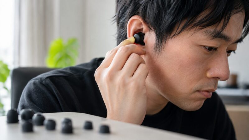 イヤーチップと装着位置を調整して音質を確認する日本人男性