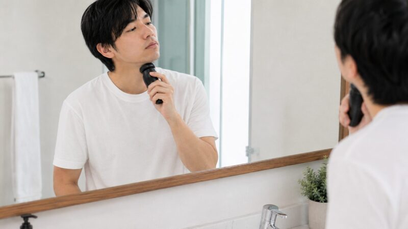 パームインシェーバーをアゴ下に当てにくそうに使う男性