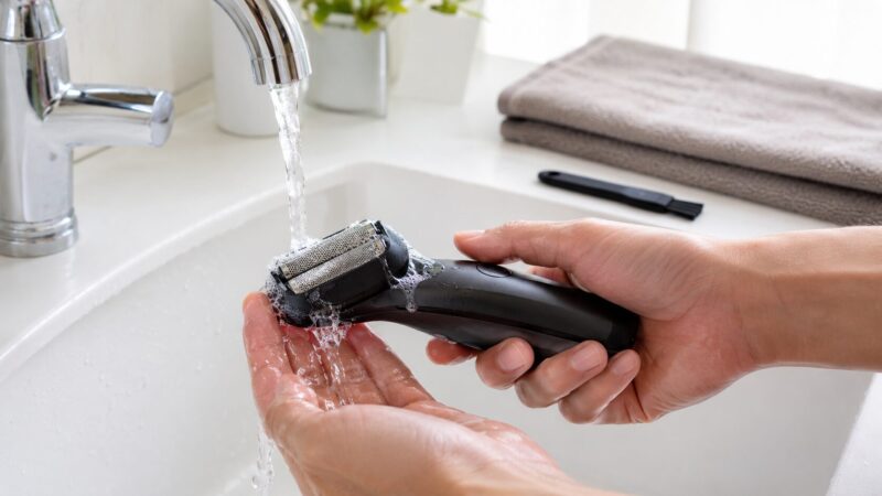 洗浄機なしの電気シェーバーを水洗いして清潔に手入れする様子