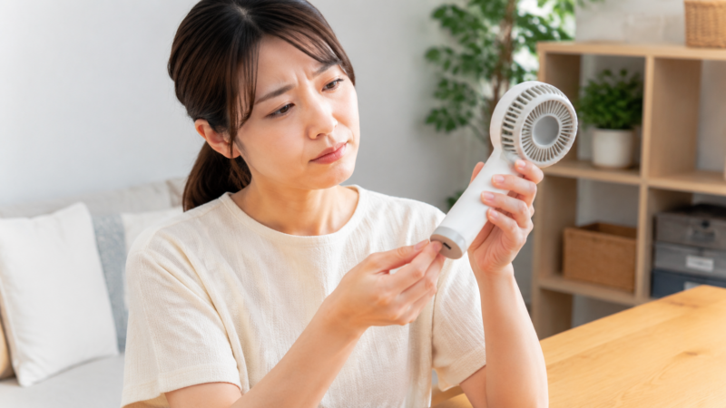 ハンディファンの外装と充電口を点検する日本人女性
