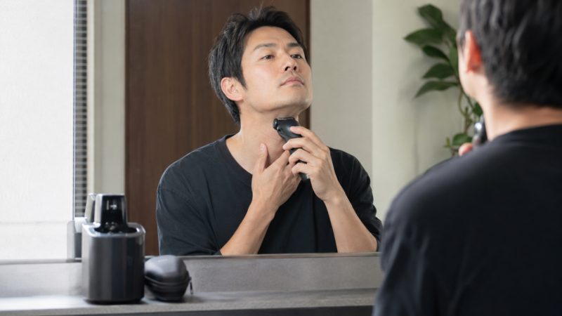 コンパクトヘッドの電気シェーバーで首やアゴ下を丁寧に剃る日本人男性
