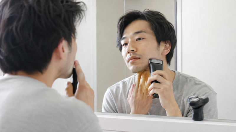 初めて往復式電動シェーバーを使い鏡を見ながら剃る日本人男性