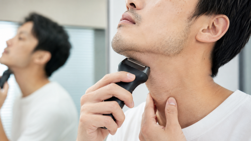 コンパクトヘッドの電気シェーバーでアゴ下の寝たヒゲを剃る日本人男性